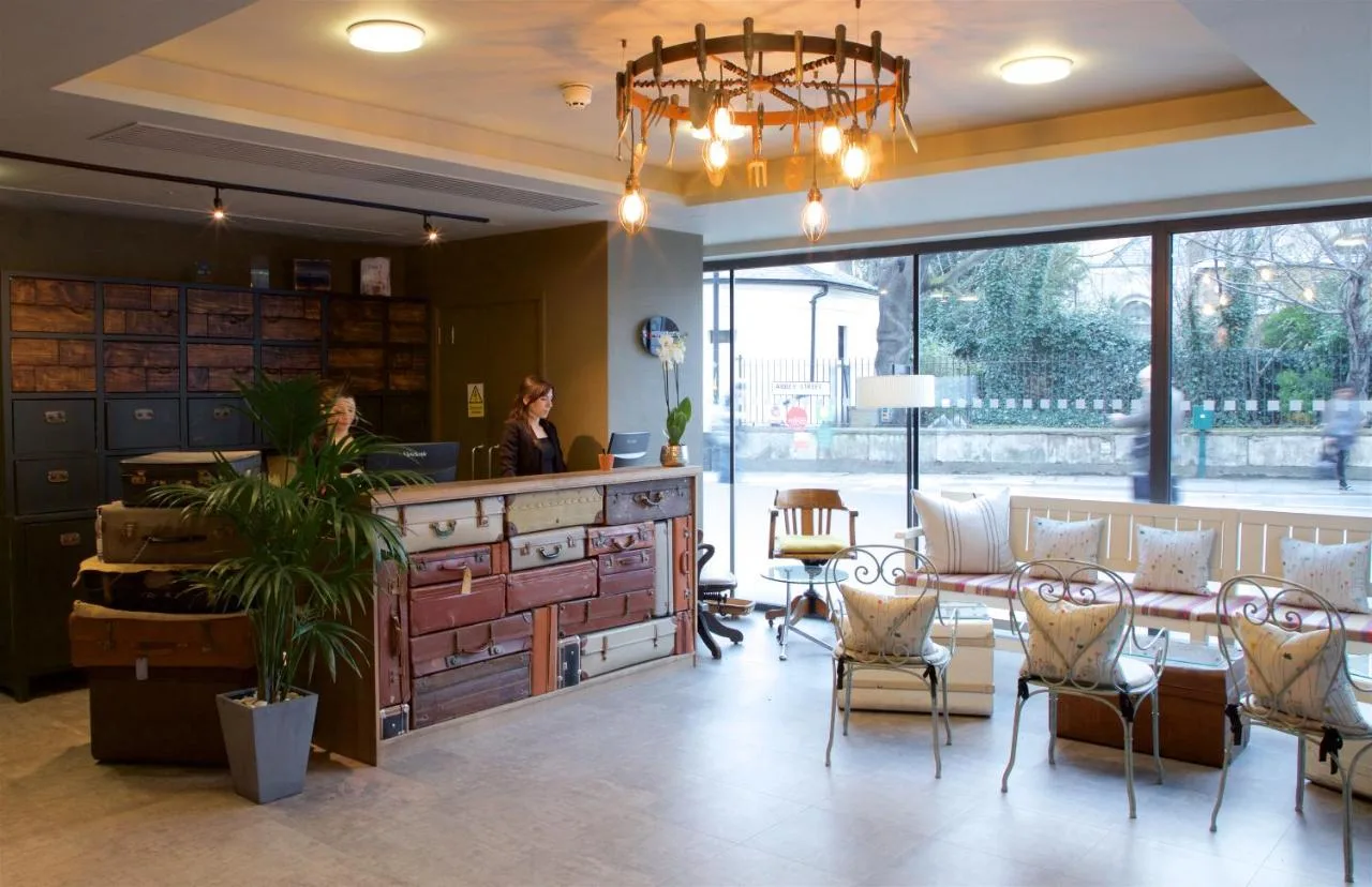 a woman standing in a lobby with a table and chairs at Bermondsey Square Hotel - A Bespoke Hotel in London