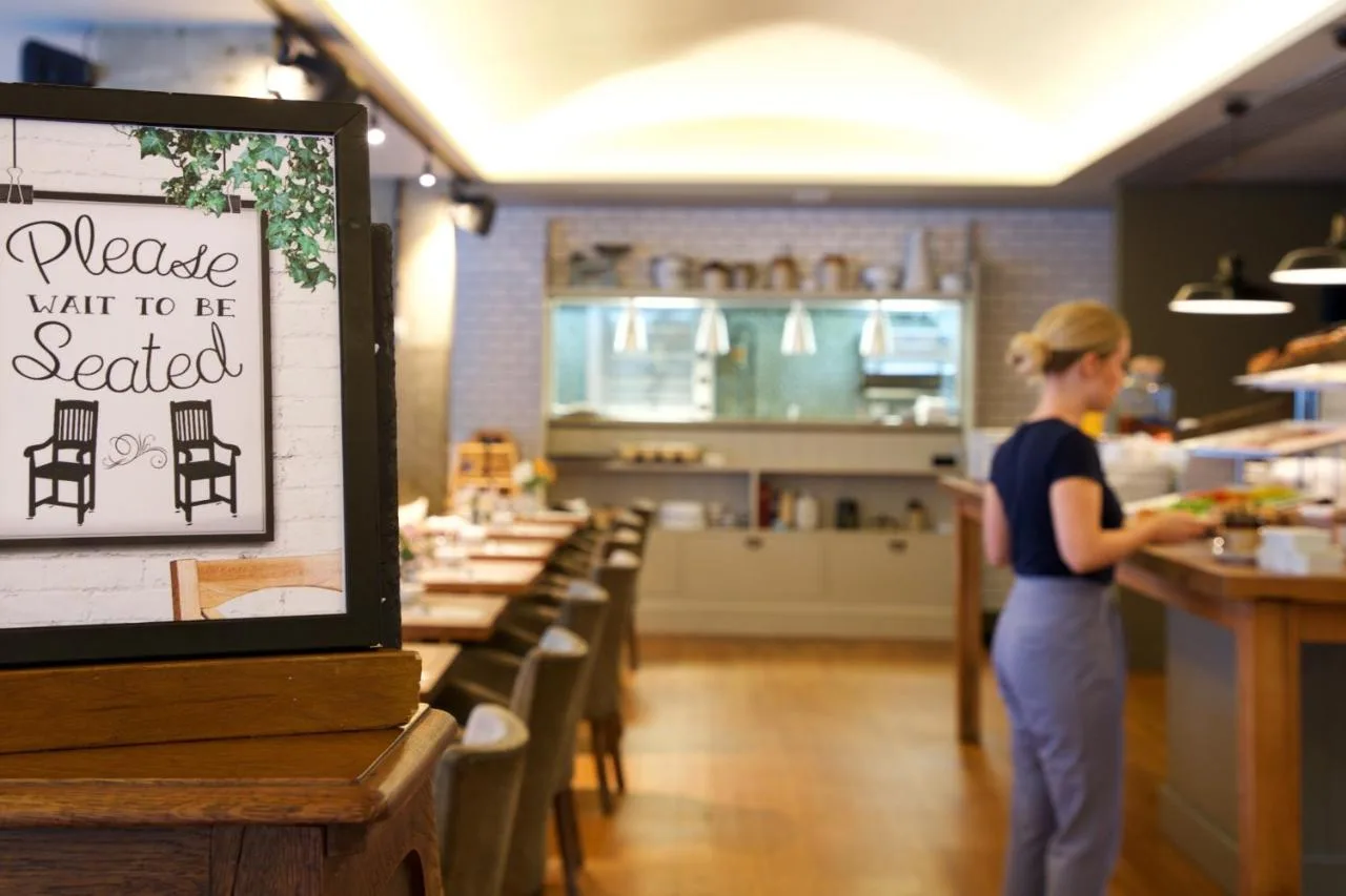 a woman standing at a counter in a restaurant at Bermondsey Square Hotel - A Bespoke Hotel in London